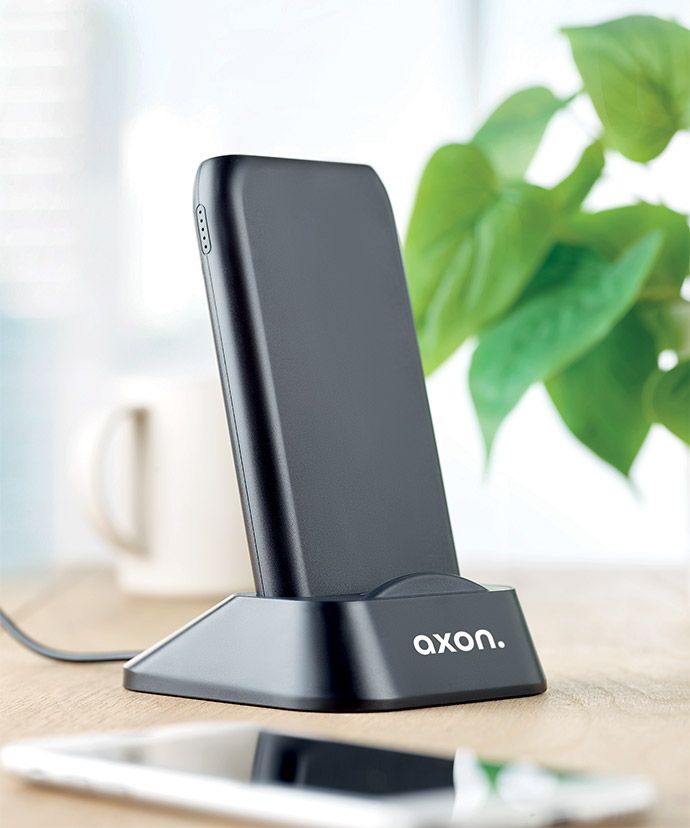 Caricabatterie senza fili nero personalizzato su un tavolo. Gadget personalizzati per l'ufficio.